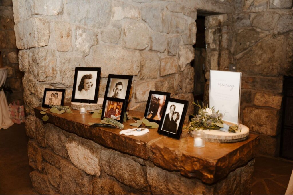 A memory table displays black-and-white family photos against a stone wall, honoring loved ones in an intimate setting. Thoughtful touches like this can make out-of-town guests feel at home at your Santa Fe wedding.
