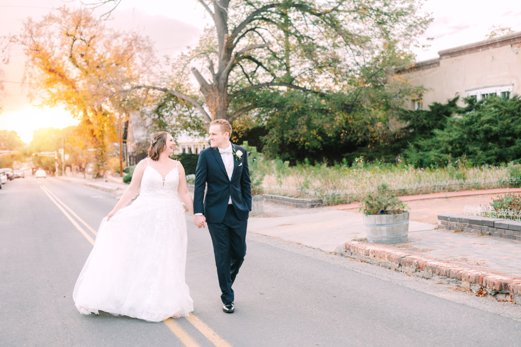 A wedding couple walks hand in hand at sunset near downtown Santa Fe—just minutes from La Posada in Santa Fe and perfect for golden hour photos.