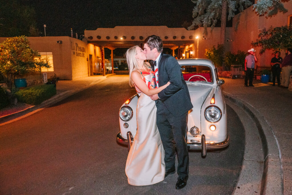 A couple’s grand exit at La Posada in Santa Fe, captured in front of the historic entrance with a vintage getaway car.