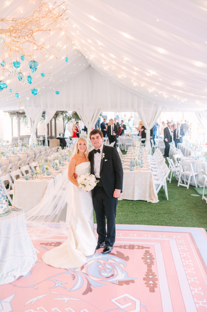 Wedding couple standing in a classic tented wedding reception at La Posada in Santa Fe with string lights, soft draping, and elegant blue-toned decor.