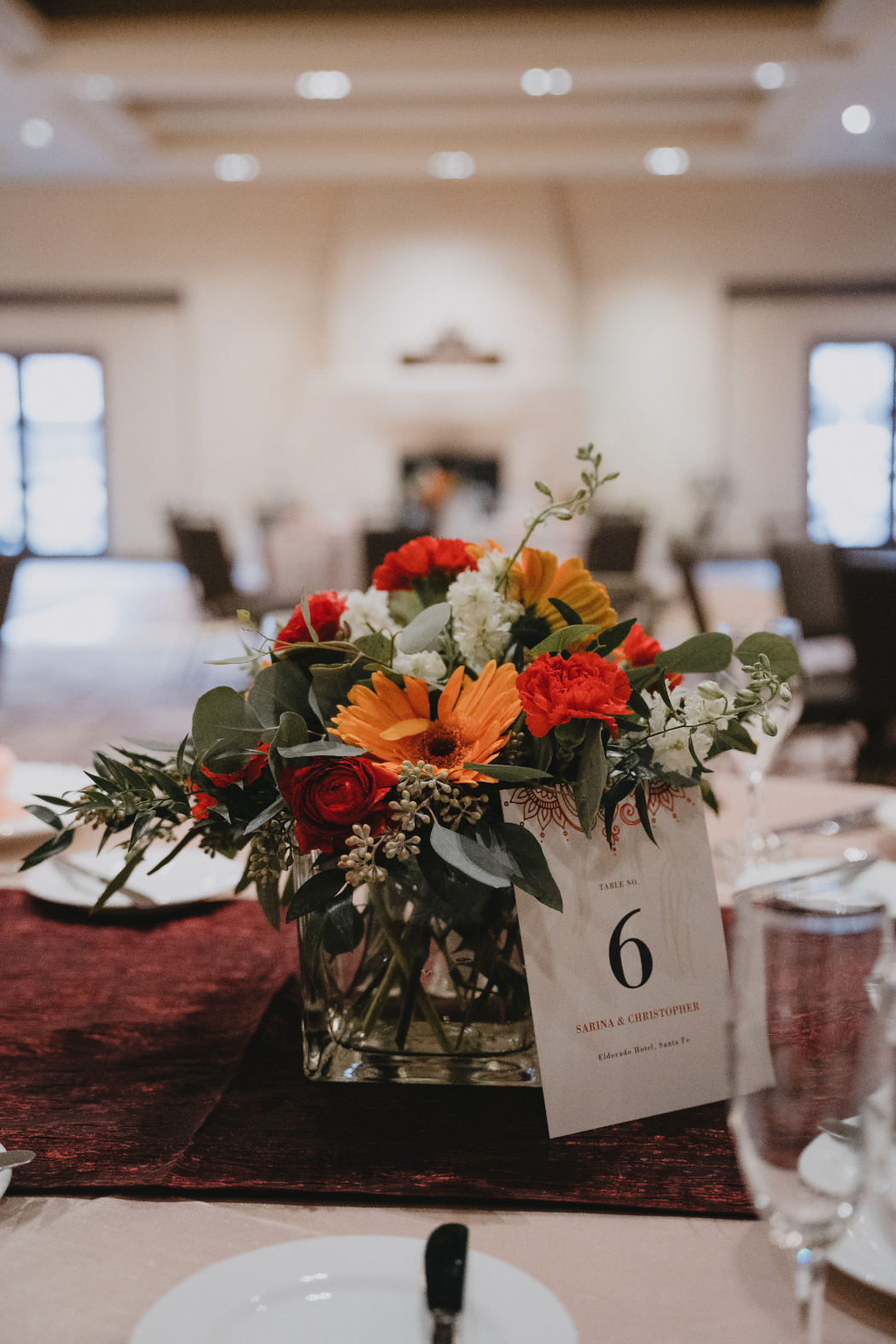 Bold floral centerpiece with orange and red blooms on reception table.