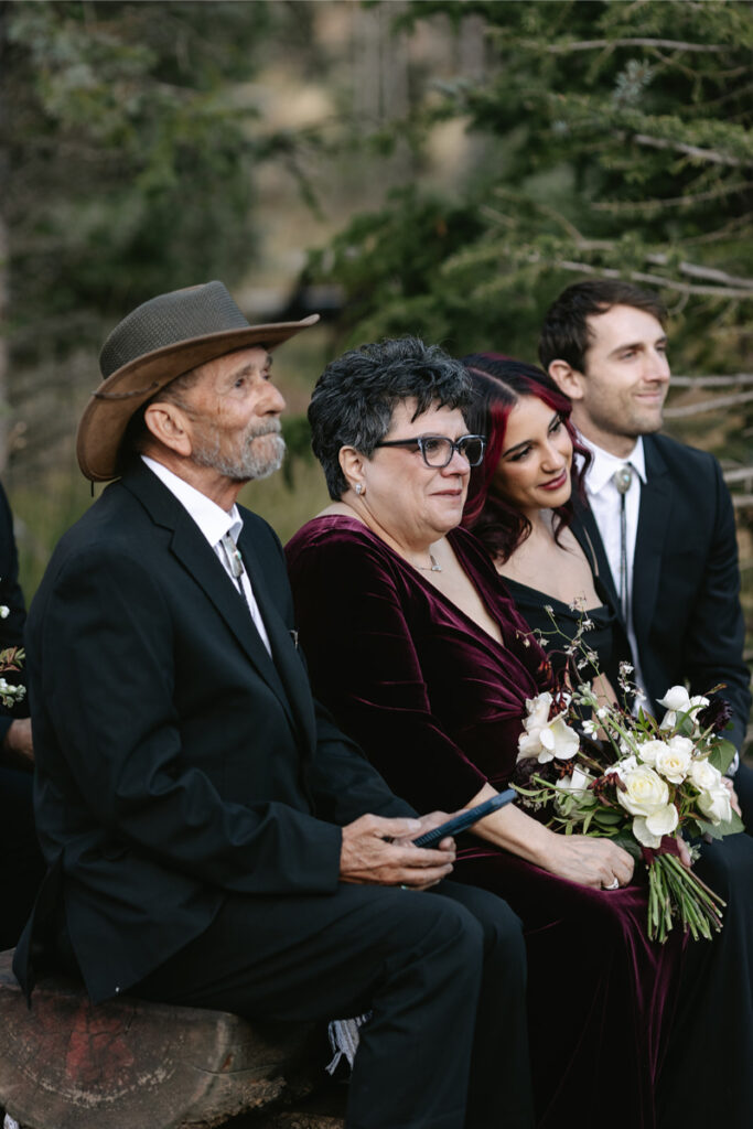 Family watching wedding ceremony in black and maroon wedding dress codes.