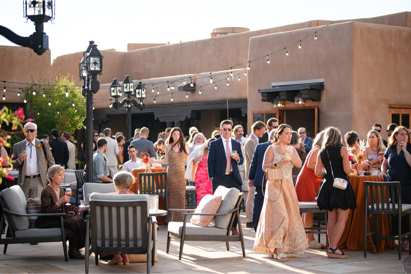 Cocktail hour following wedding ceremony features several guests and lounge seating for elevated guest experience.