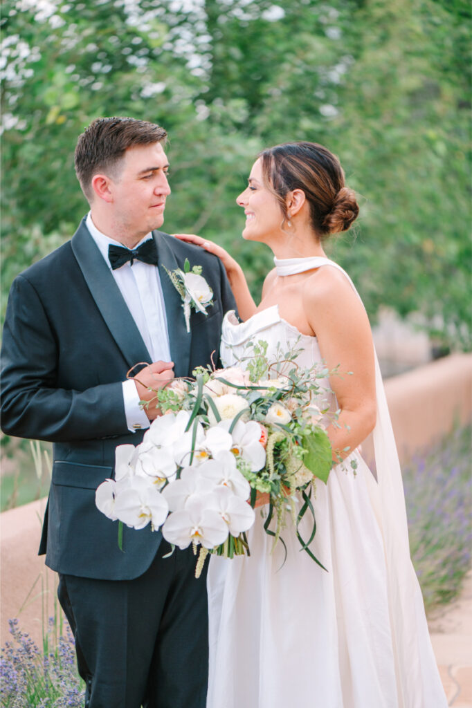 Bride and groom pose together with luxury flower bouquet for their wedding portraits.