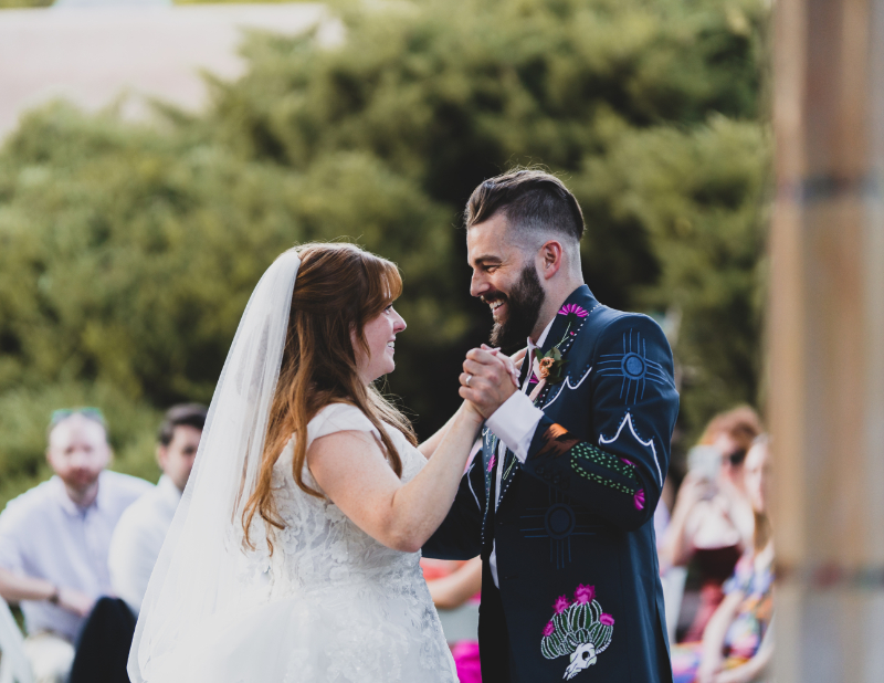 Bride and groom smiling during their first dance, their wedding day order of events running smoothly.