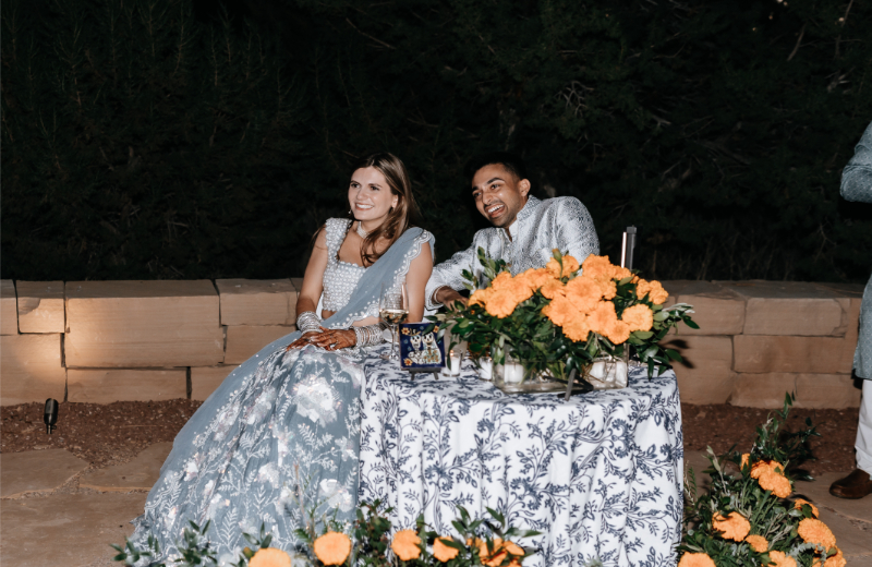 Bride and groom sit at sweetheart table during wedding reception dinner.