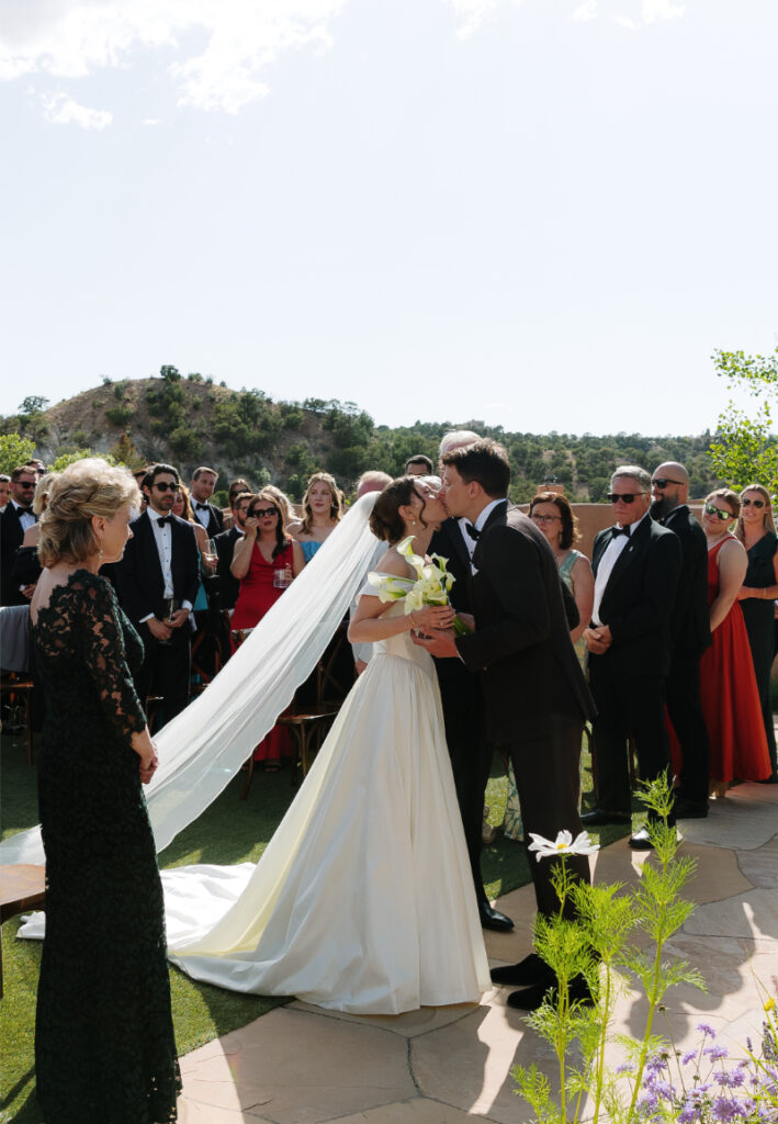 Bride kisses groom as she reaches the end of the aisle during their unplugged ceremony in New Mexico.