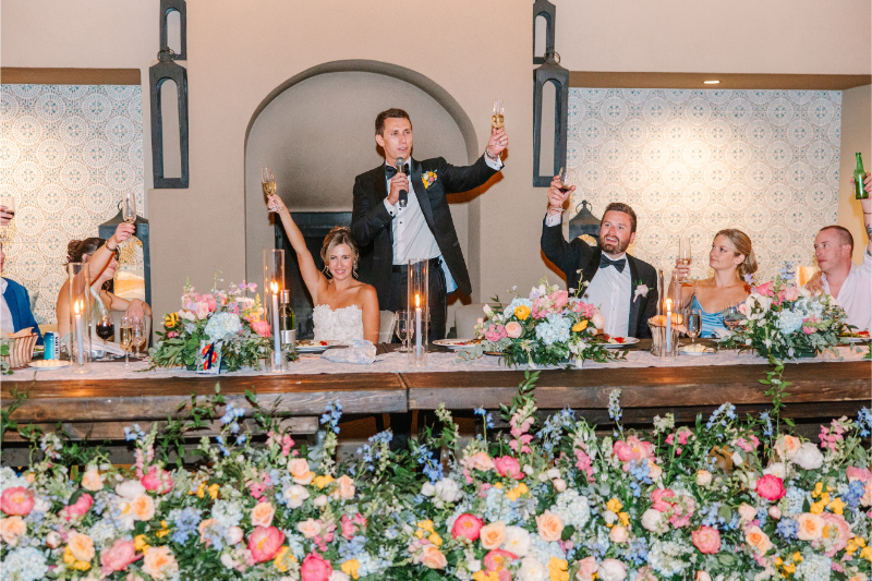 Bride and groom raise a toast during their reception, completely in the moment and not worrying about a timeline because they searched what does a wedding planner do and decide to hire Lace and Bow for their big day.