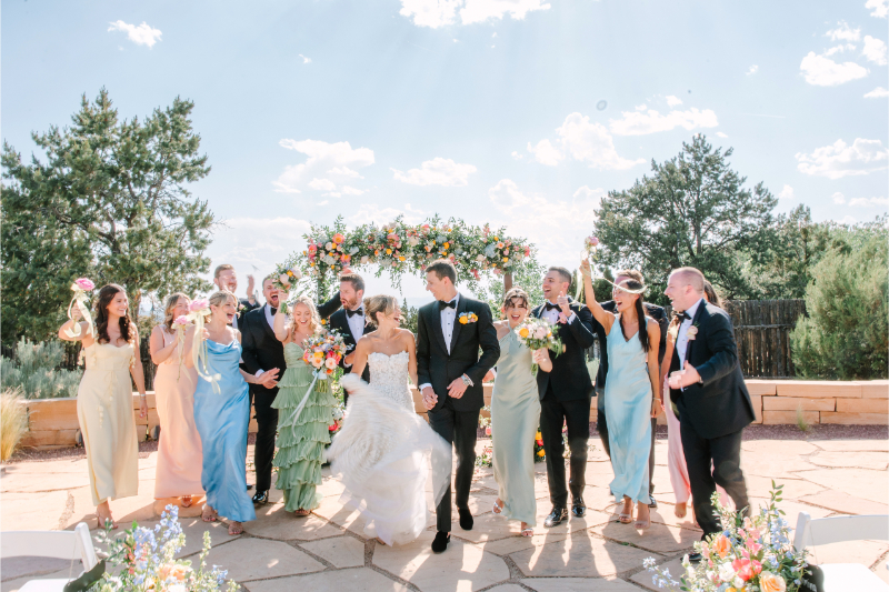 Bride and groom walk with wedding party for portraits in their ceremony space.