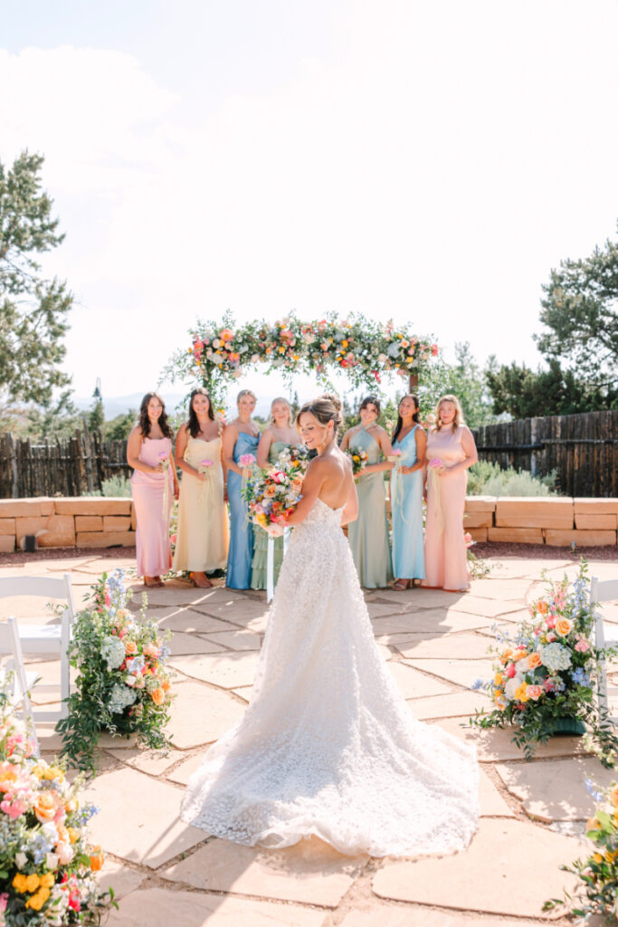 Bride stands holding bouquet, surrounded by lovely arrangements from one of the best Albuquerque florists.