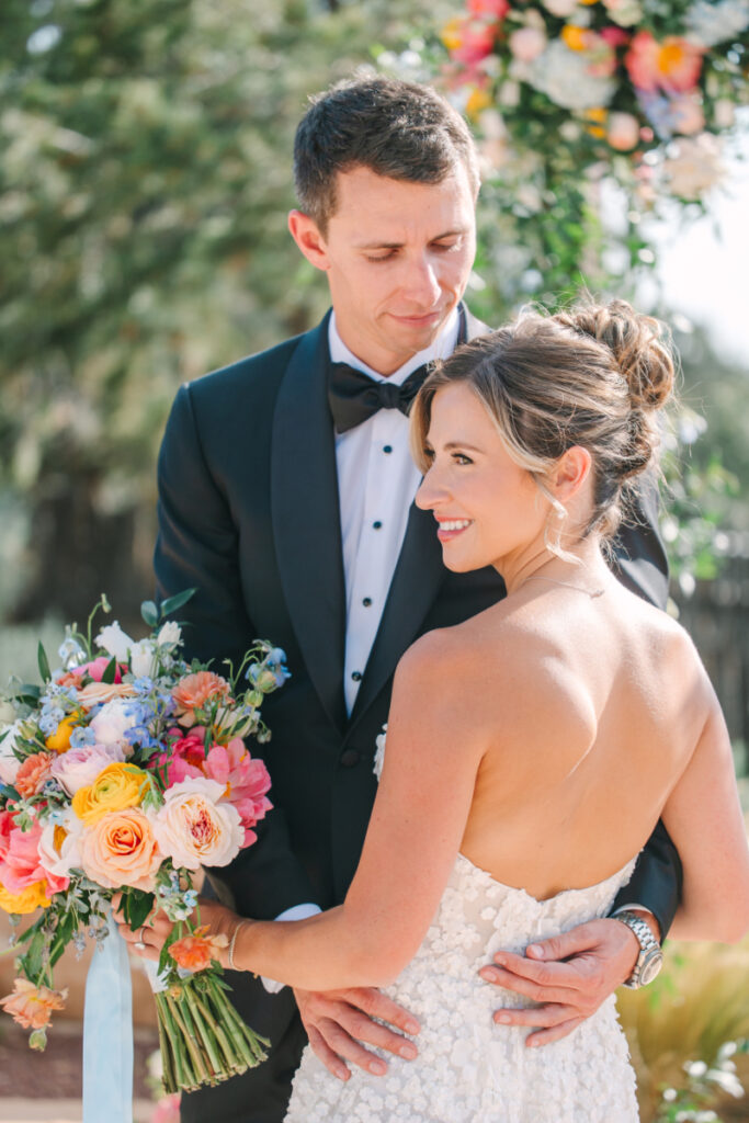 Bride holds bouquet arranged by one of the best Albuquerque florists, as she takes portraits with her husband.