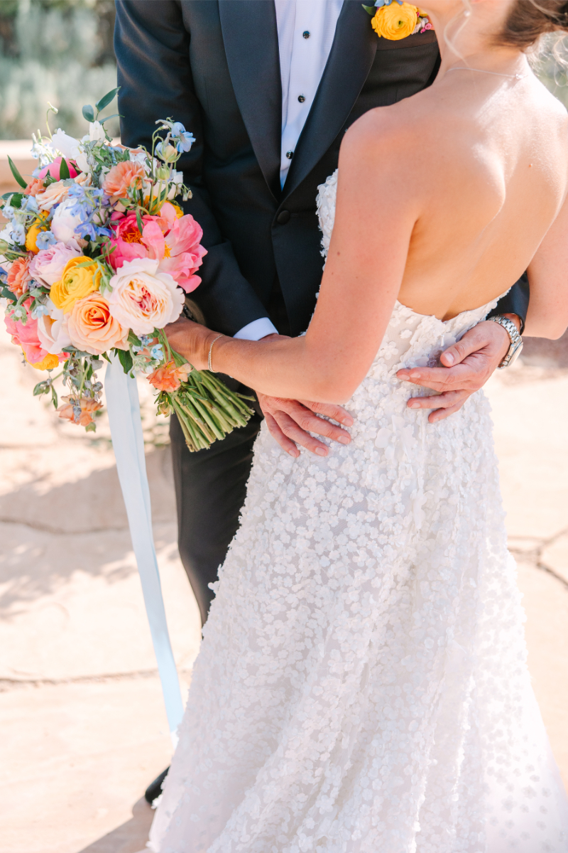 Bride holds bouquet arranged by one of the best Albuquerque florists, as she takes portraits with her husband.