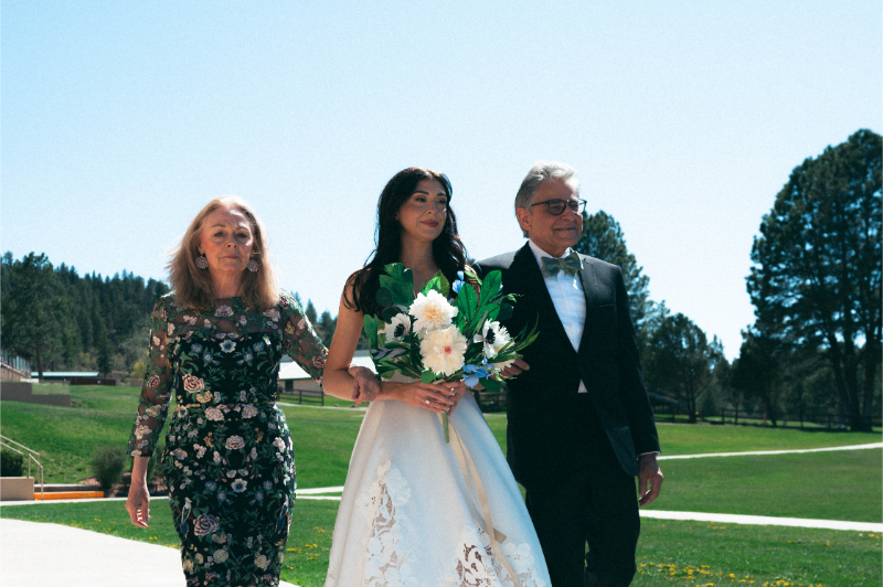 Bride is escorted down the aisle by her mother and father.