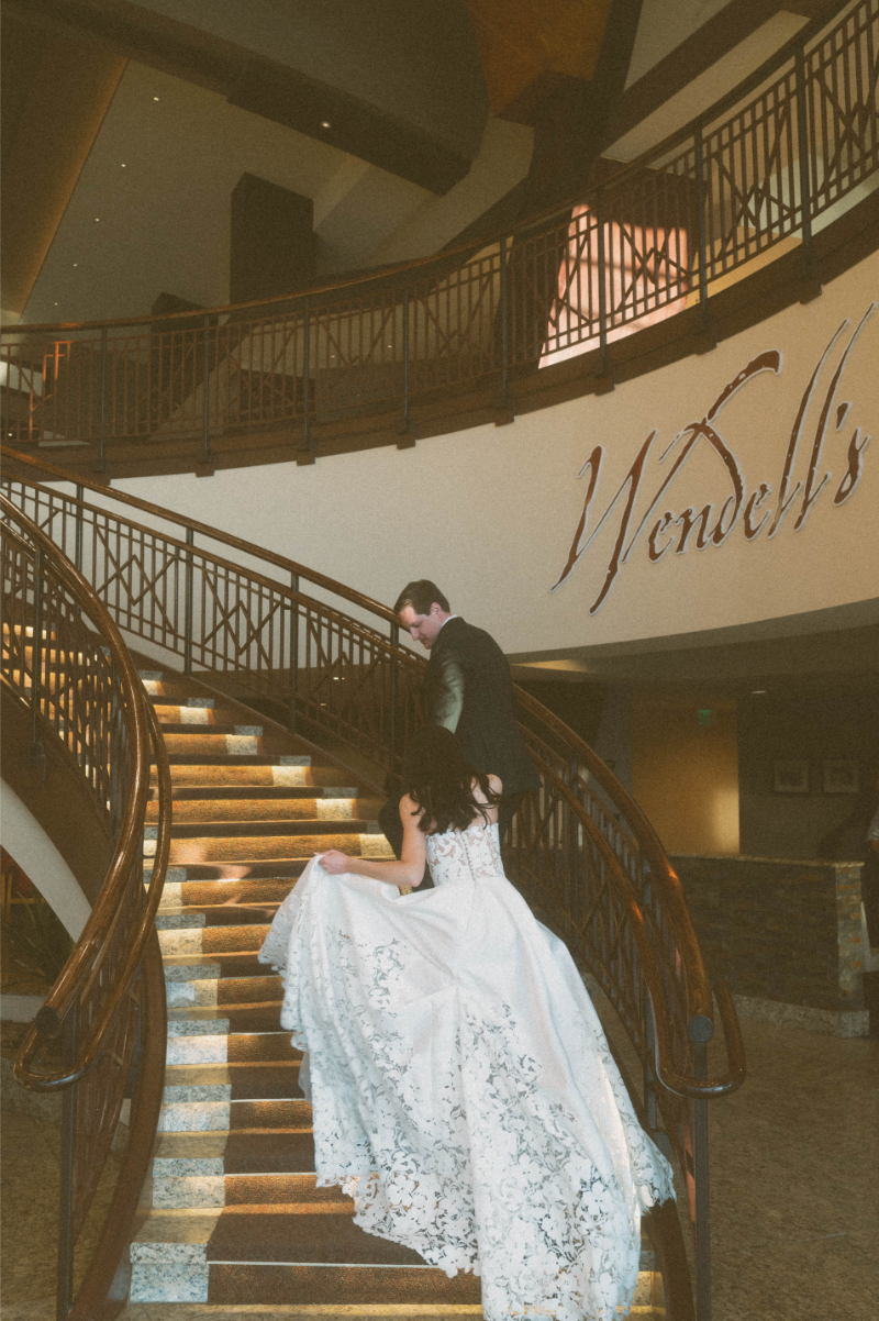 Bride and groom walk up grand staircase at Inn of Mountain Gods.