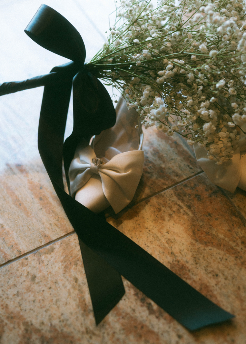 Bridal details for simple wedding including babys breath bouquet in a black wrap, and heels.