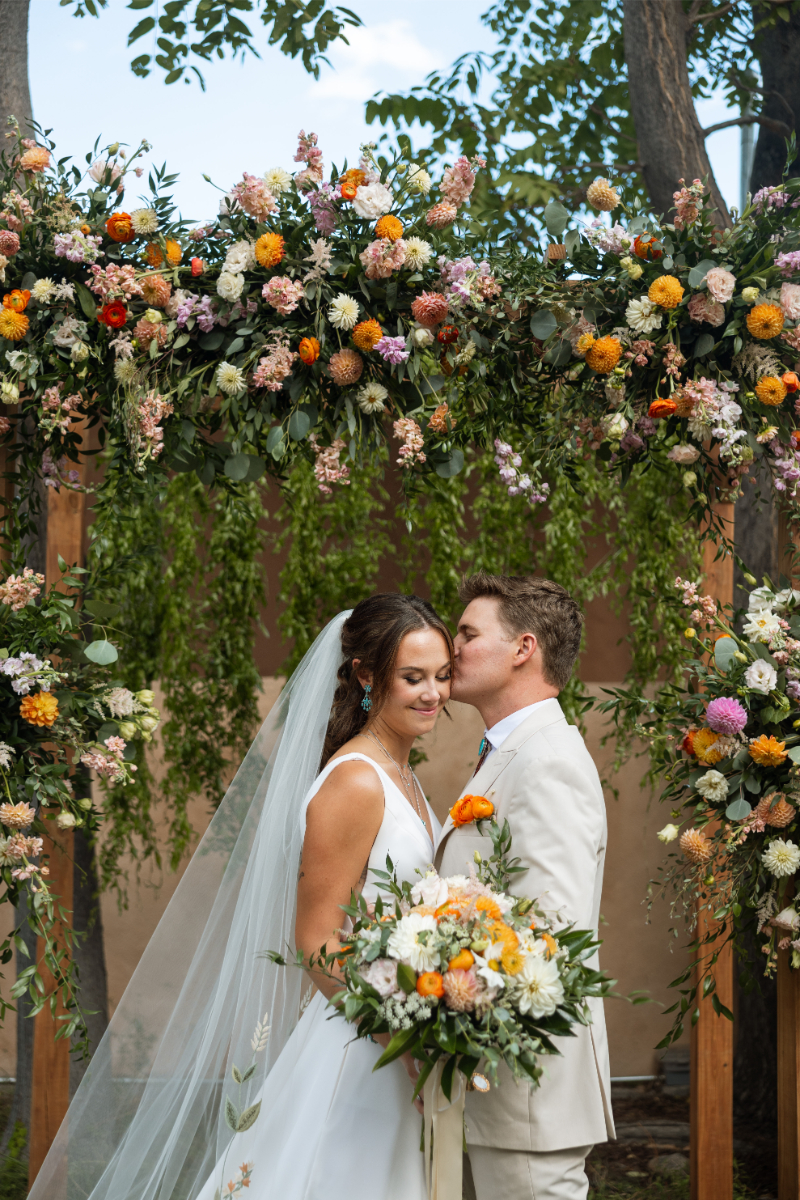 Bride and groom share kiss at altar.