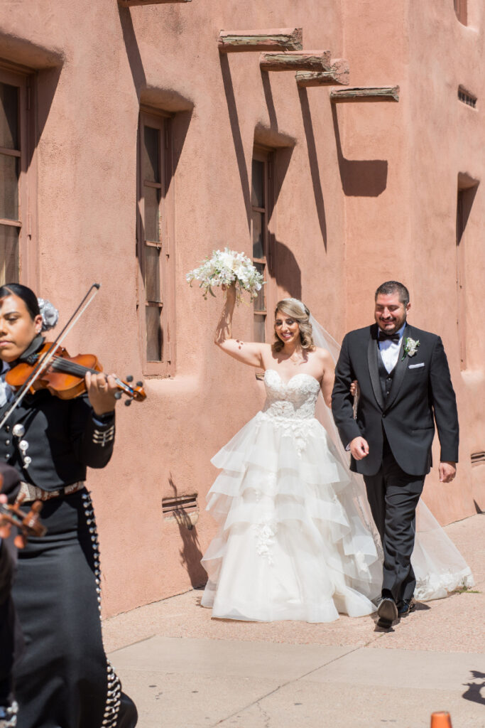 Bride and groom follow behind mariachi band as they march their guests toward cocktail hour. 