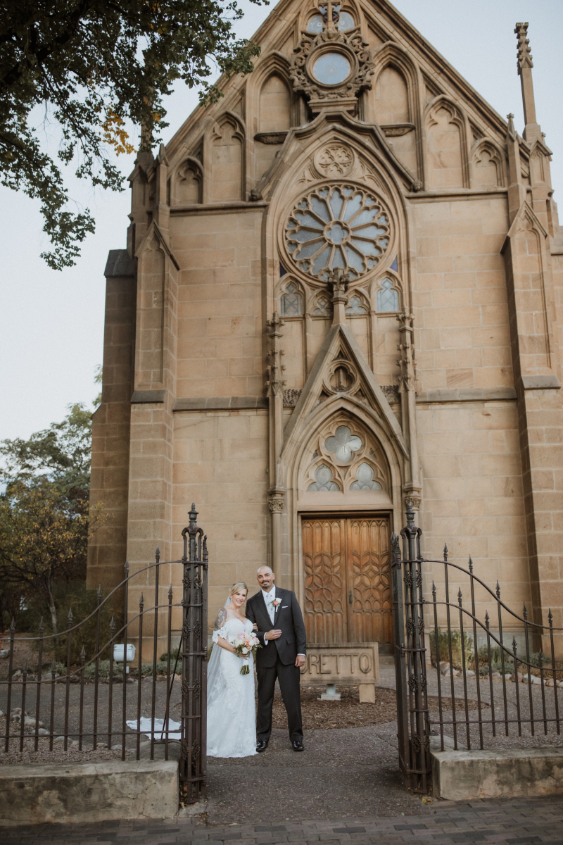 Bride and groom pose together outside Loretto Chapel.