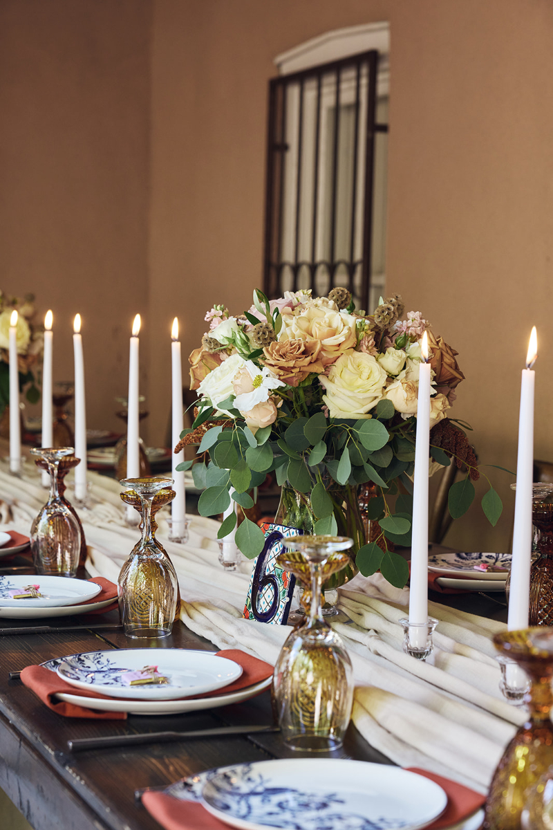 Table set with boho decor, flower arrangement and taper candles for wedding reception.