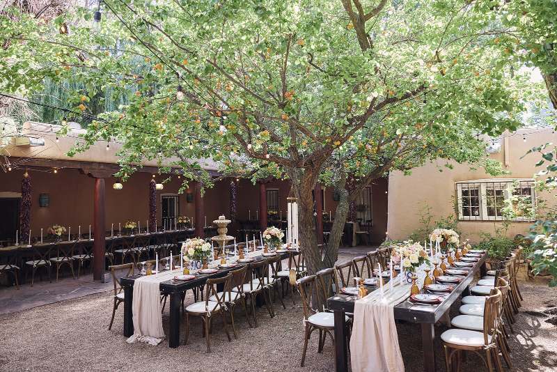 Backyard wedding reception setup with long communal tables.