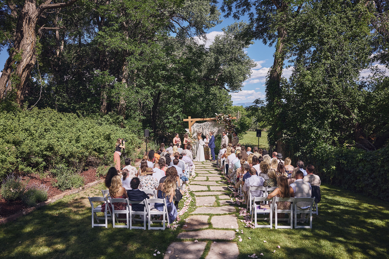 Backyard wedding ceremony surrounded by trees and a long stone walkway leading to the altar.