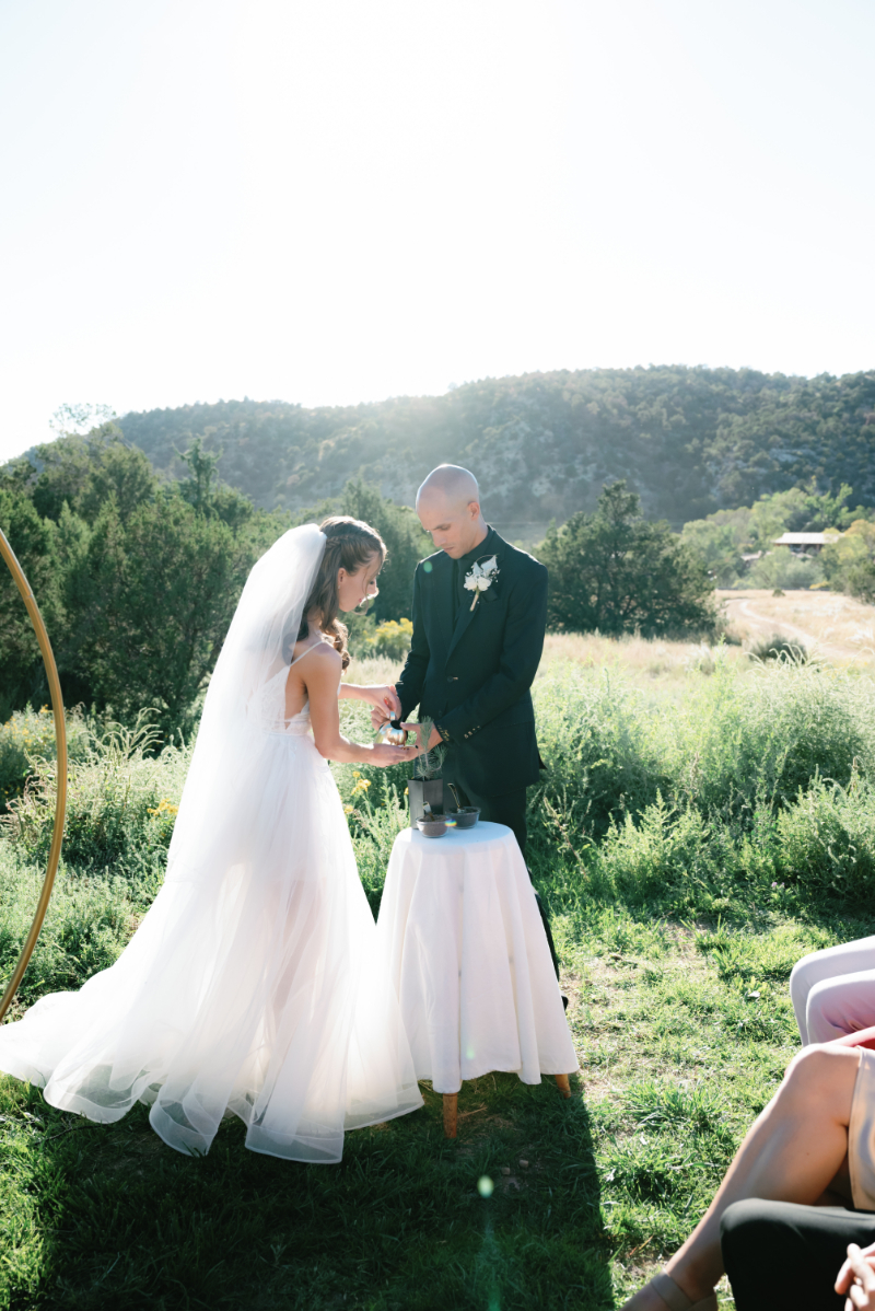 Bride and groom pour water from gold watering can into a tree they planted for a unity ceremony during their non-traditional nuptials.