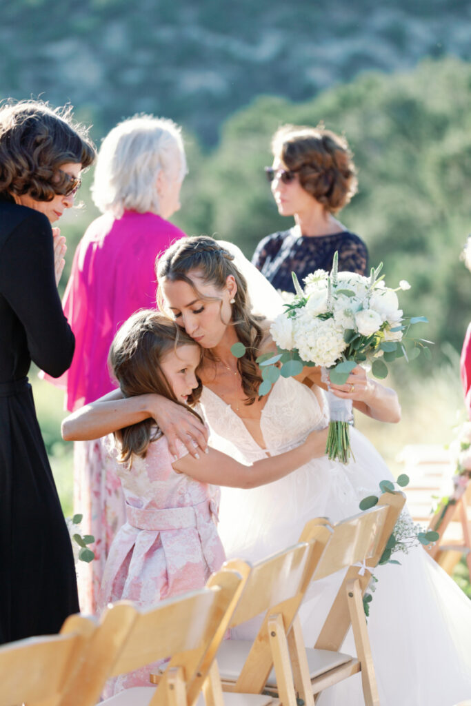 Bride crouches down to hug younger guest once she gets down to the end of the aisle during her non-traditional nuptials ceremony.