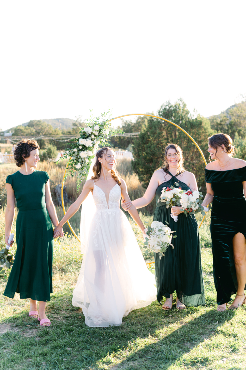 Bride stands for portraits with her bridal party in green dresses.