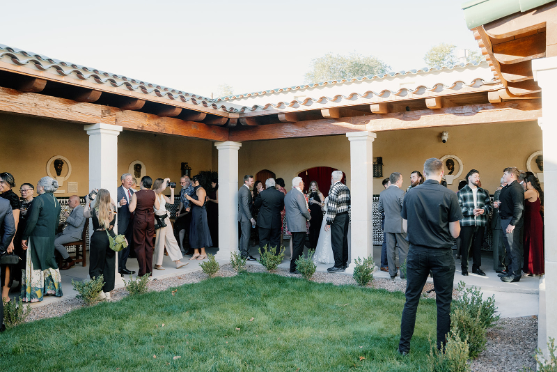 Guests mingle during cocktail party on mansion lawn.