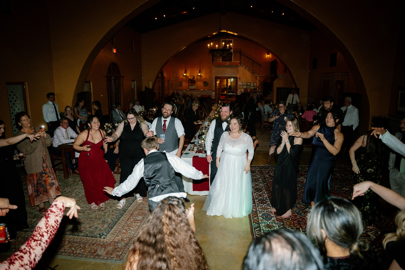 Wedding guests stand in circle as they watch another guest dance in the middle of them.
