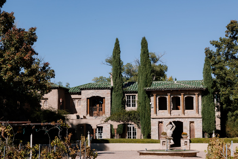 Front view of one of New Mexico's mansion wedding venues with a fountain out front and beautiful landscaping.