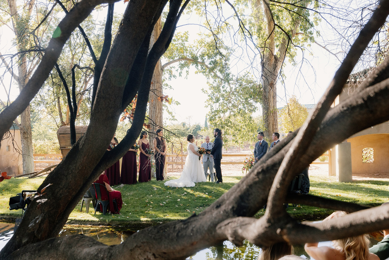 Bride and groom exchange vows on mansion wedding venues lawn surrounded by their family and friends.