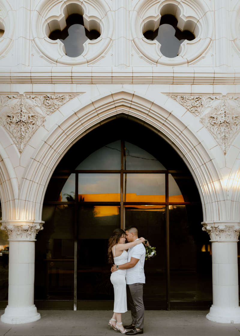 Engaged couple stand under building arch, enjoying a slow start to their wedding planning timeline.