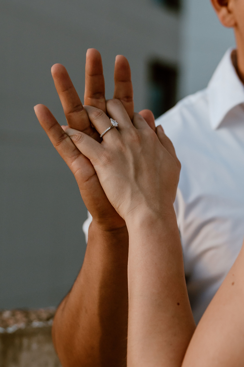 Detail shot of couple holding hands to show off engagement ring.