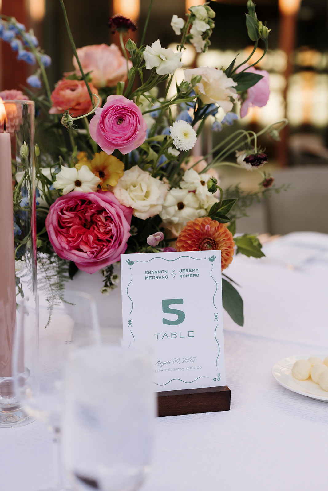 Table number sitting on reception table next to colorful floral arrangement.