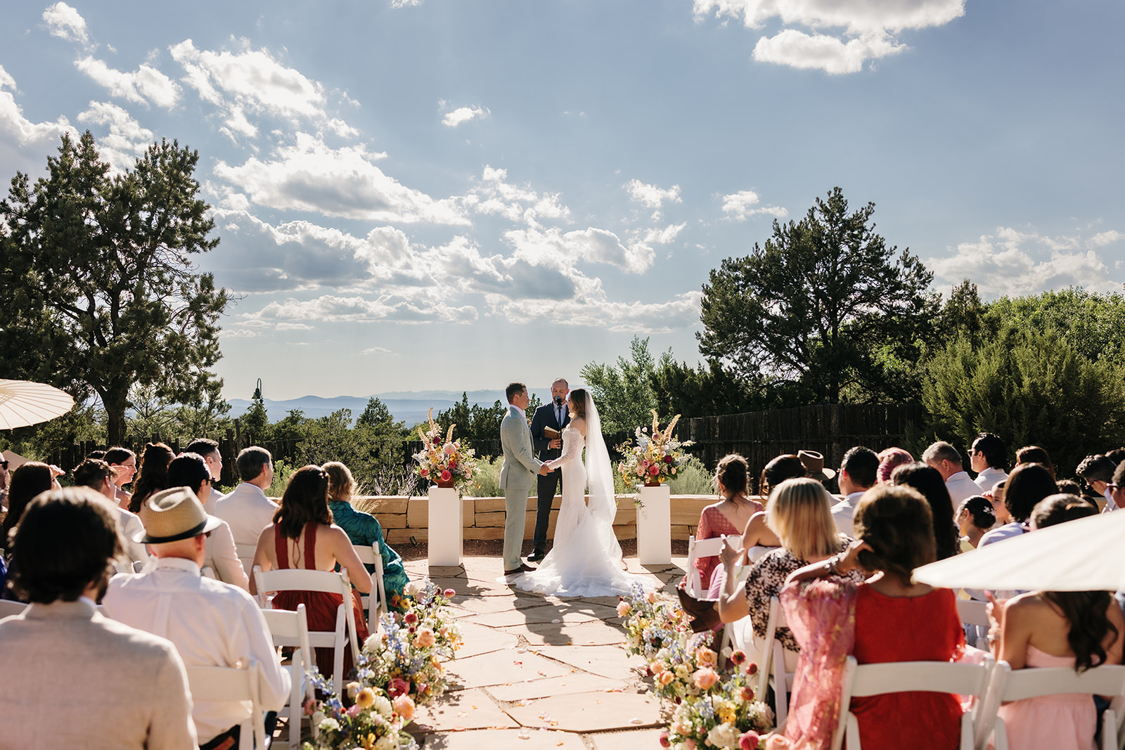 Bride and groom stand together holding hands during their ceremony at the Four Seasons Santa Fe.