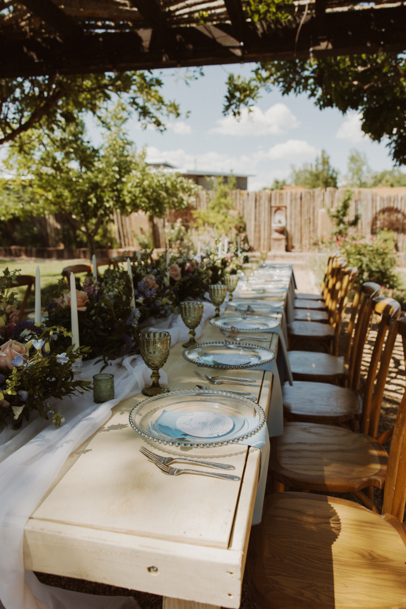 Table setting details with glass plate, pale blue napkin, butterfly name card, and floral centerpiece.