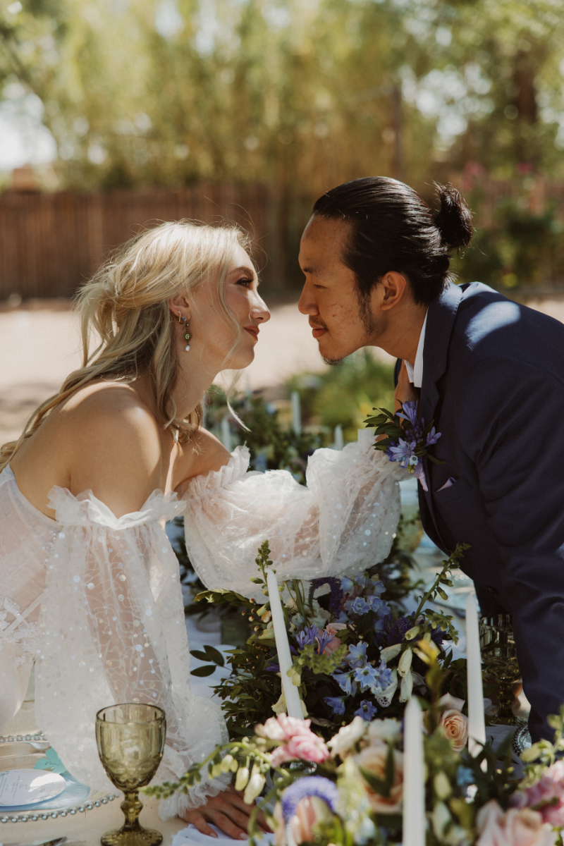 Bride and groom lean over French Chateau wedding styled table.