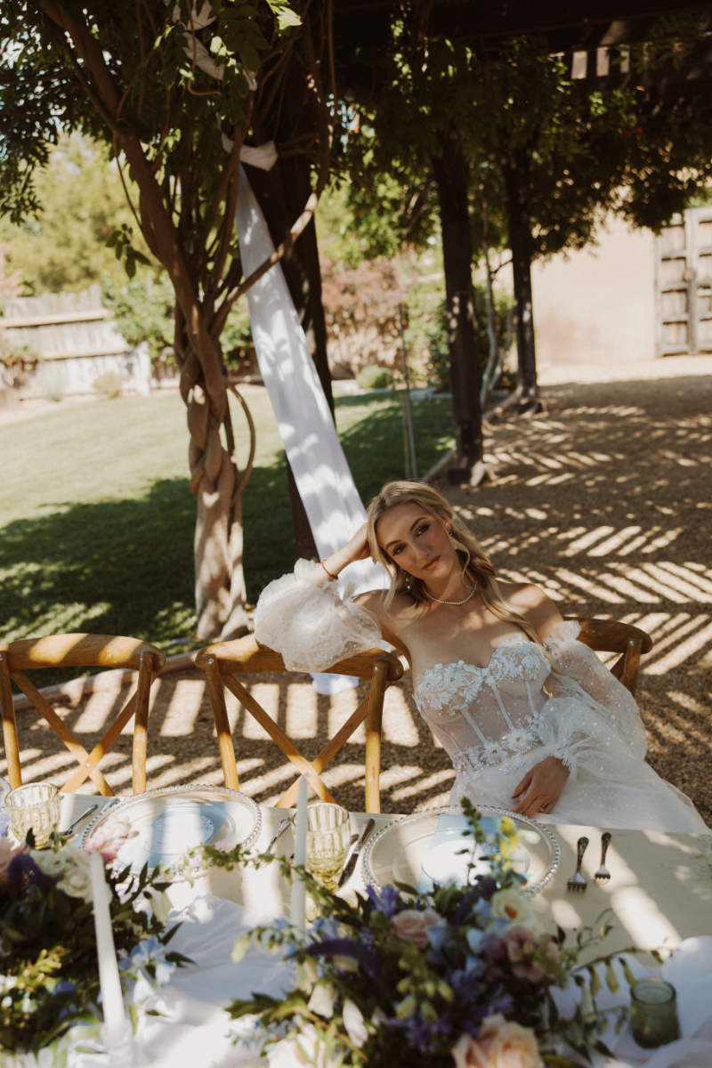 Bride sits at French Chateau wedding reception table with her head resting in her hand.