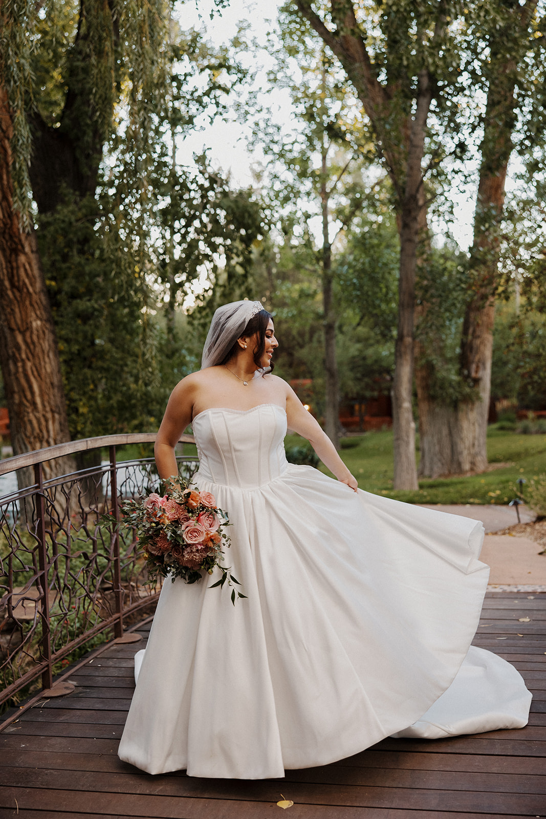 Bride twirls in her wedding dress with bouquet in hand as her photographer captures portraits.