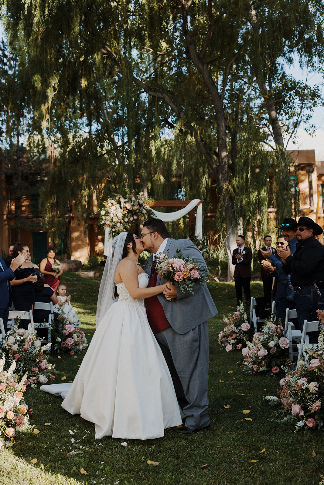 Bride and groom stop in the middle of the aisle to share a kiss during their recession.