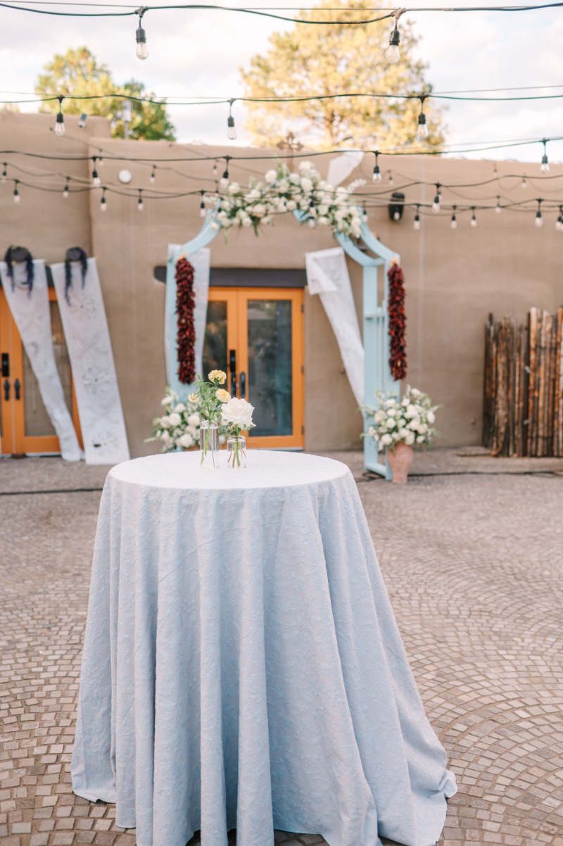 Cocktail hour table decorated with blue linens and white florals.
