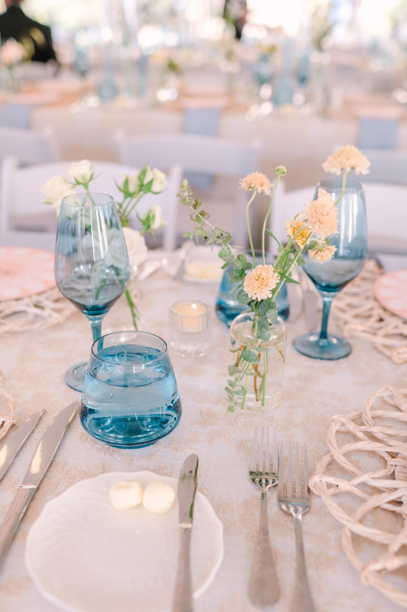 Table setting for wedding reception with blue glassware.