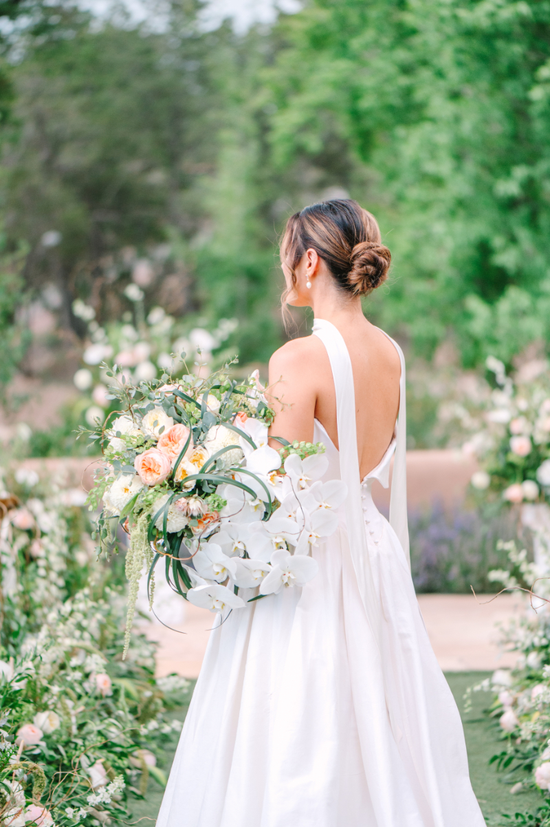 Bride faces away from camera as she holds her whimsical bouquet, a perfect example of bridal bouquet ideas brought to life in Santa Fe.