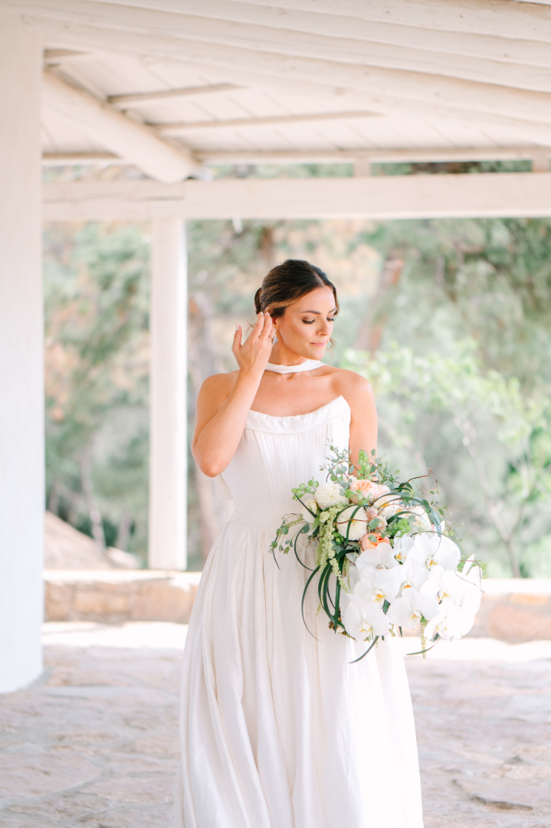 Bride tucks hair behind her ears as she stands for portraits - a perfect example of whimsical and organic bridal bouquet ideas.