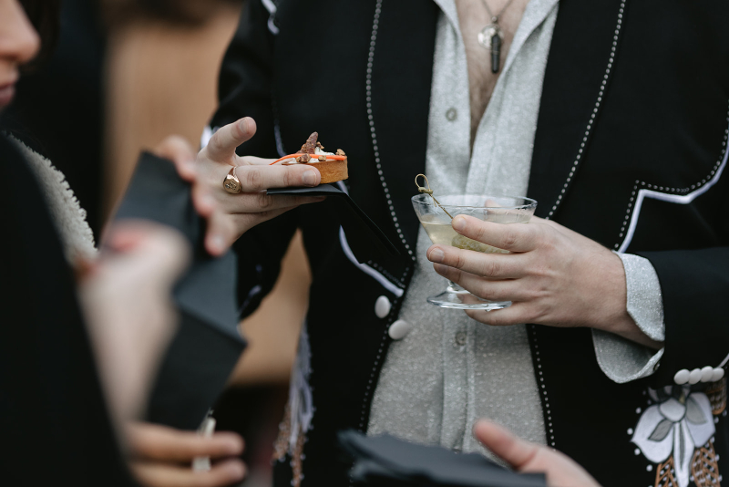 Guest at cocktail hour holds signature drinks in hand.