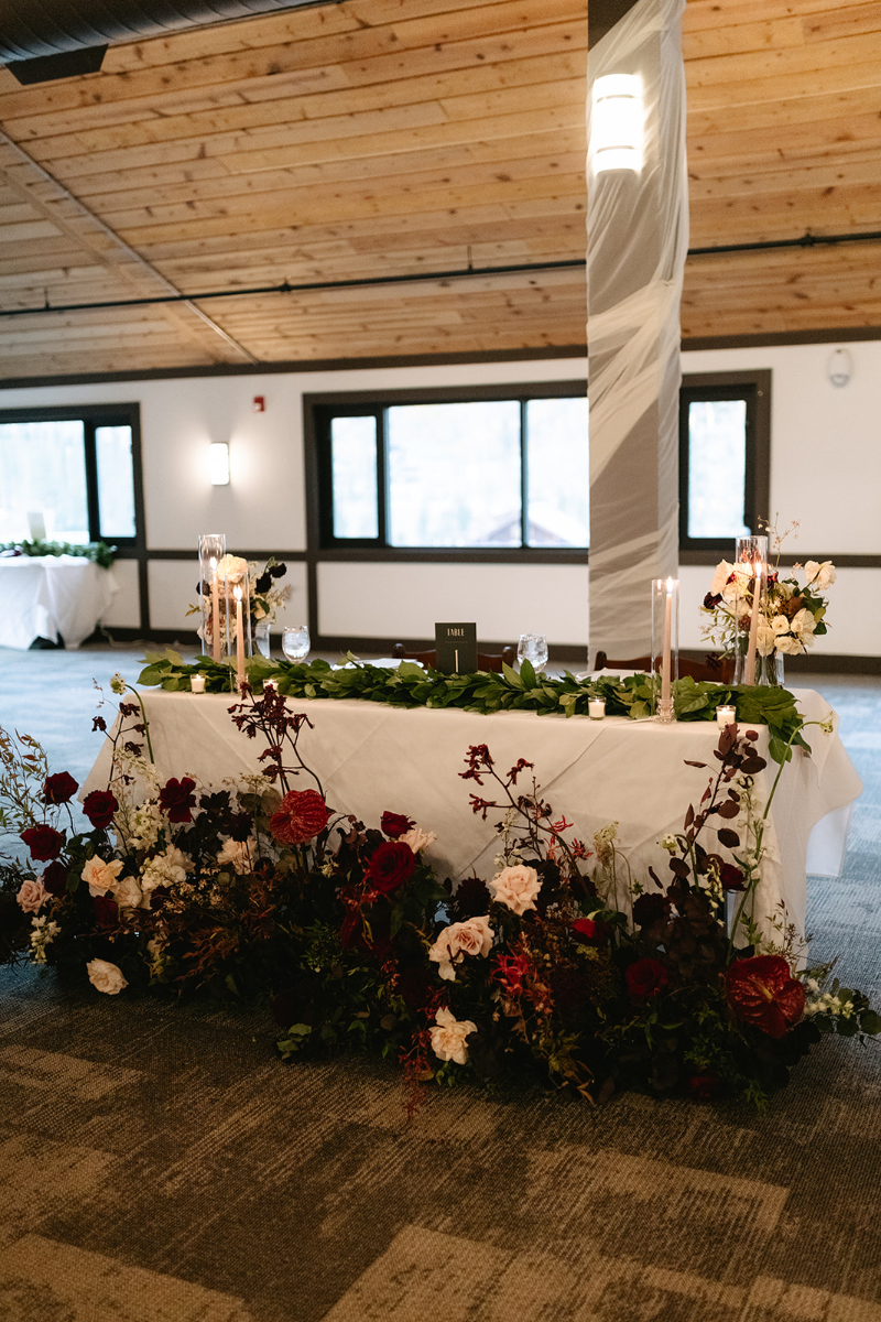 Sweetheart table surrounded by red floral meadow.