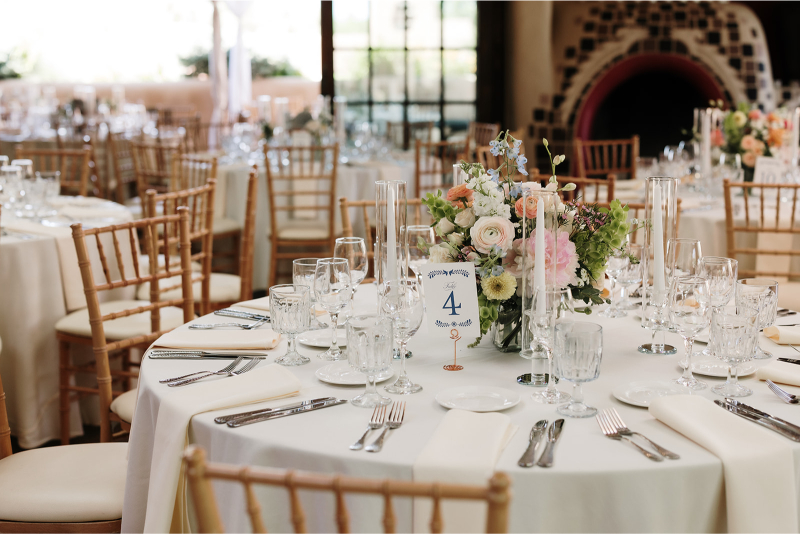 Table decorated with spring centerpiece ideas including low floral arrangement and taper candles in votives.