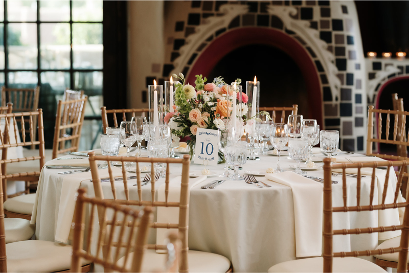 Table decorated with spring centerpiece ideas including low floral arrangement and taper candles in votives.