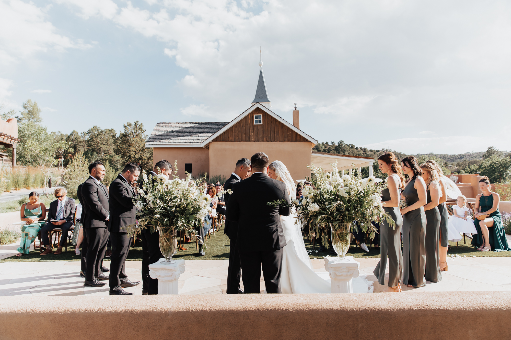 Bride and groom stand at altar surrounded by their friends and family, photographer capturing them from behind so the entire venue is in view for their wedding in Tennessee.